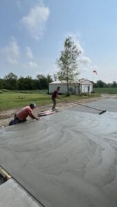 Workers hand troweling a fresh concrete slab near an outbuilding in Cary, NC